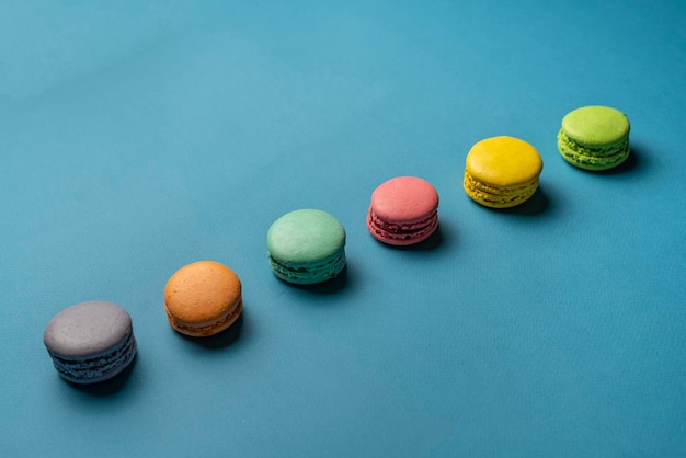 Um conjunto multicolorido de biscoitos de macaroons franceses em fundo pastel