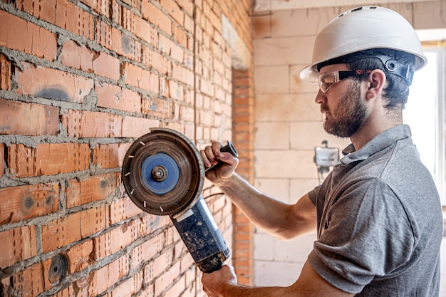 Um construtor profissional de roupas de trabalho trabalha com uma ferramenta de corte