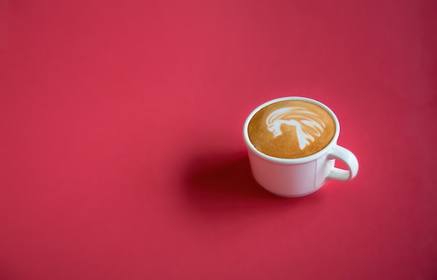 Um copo branco da arte quente do latte do café no fundo vermelho com espaço da cópia. vista do topo