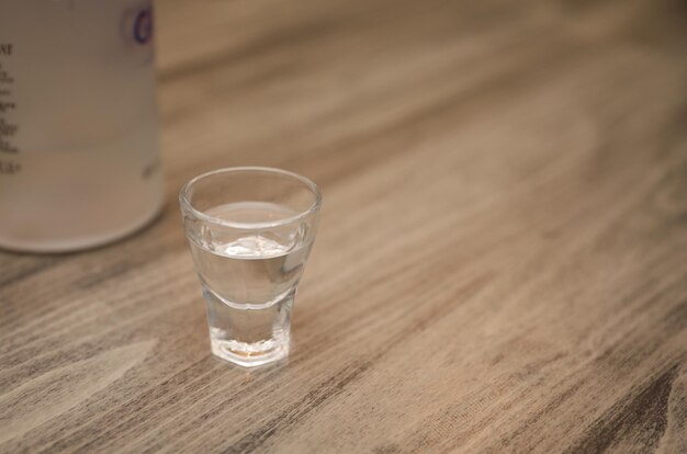 Um copo com ag está sobre uma mesa ao lado de uma garrafa de g.