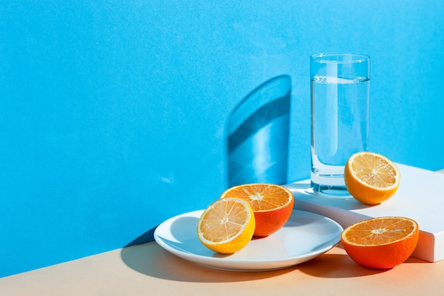 um copo com água, limão e laranja