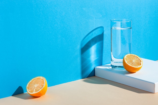 um copo com água, limão e laranja