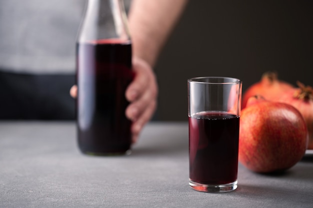 Um copo com suco de romã fica em uma superfície de concreto cinza