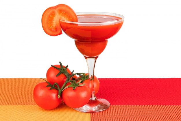 Um copo com suco de tomate com uma fatia de tomate