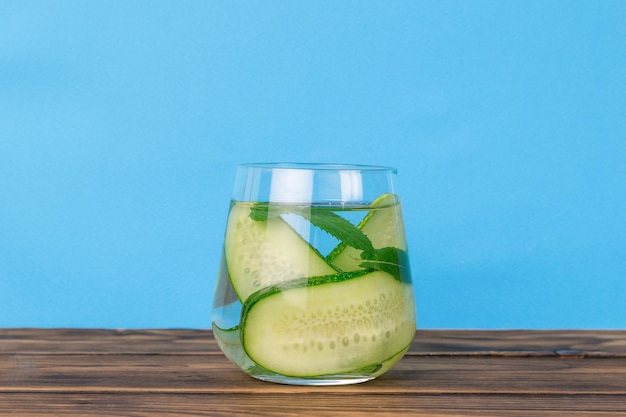 Um copo com uma bebida refrescante feita de pepinos em uma mesa de madeira