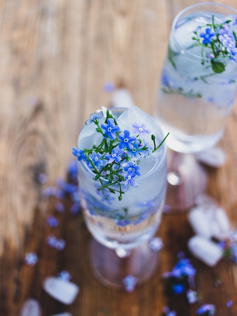 Um copo de água e cubos de gelo com flores