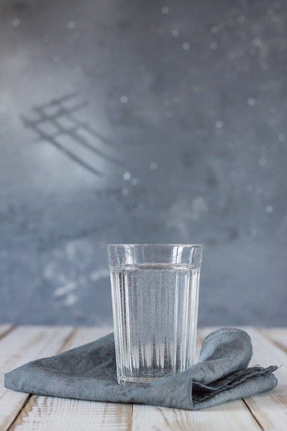 Foto um copo de água potável em um guardanapo em uma mesa de madeira. o conceito de um estilo de vida saudável.