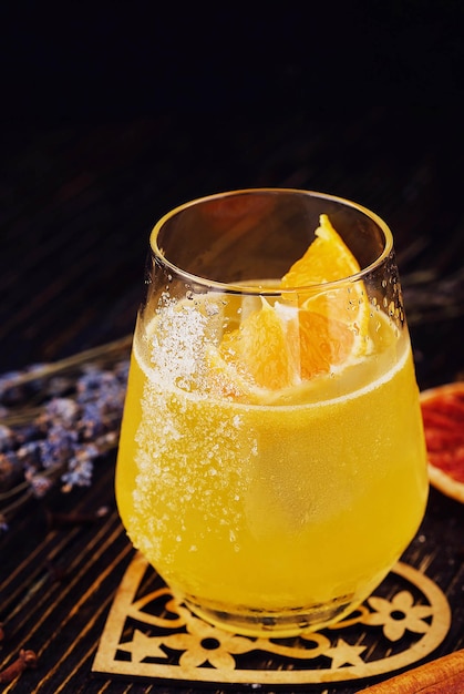 Um copo de bebida alcoólica de laranja com gelo e fatia de laranjeira