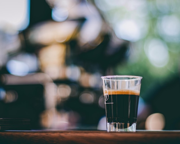 Foto um copo de café expresso em um bar com um fundo desfocado.