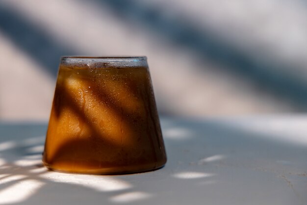 Foto um copo de café gelado. bebida gelada em um dia quente de verão. protecção solar na parede