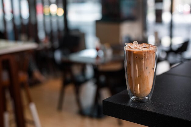 Um copo de café gelado com leite na mesa.