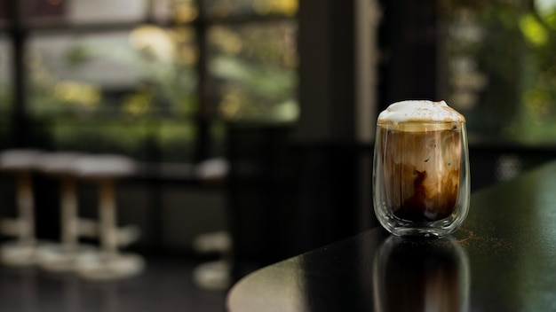 Um copo de café gelado está posicionado na bancada de um bar