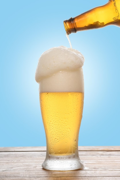 Um copo de cerveja com uma garrafa de cerveja sendo derramada nele