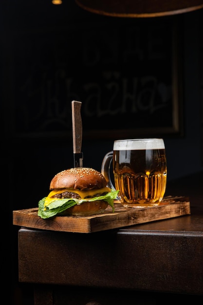 Um copo de cerveja e um hambúrguer com uma faca ao lado