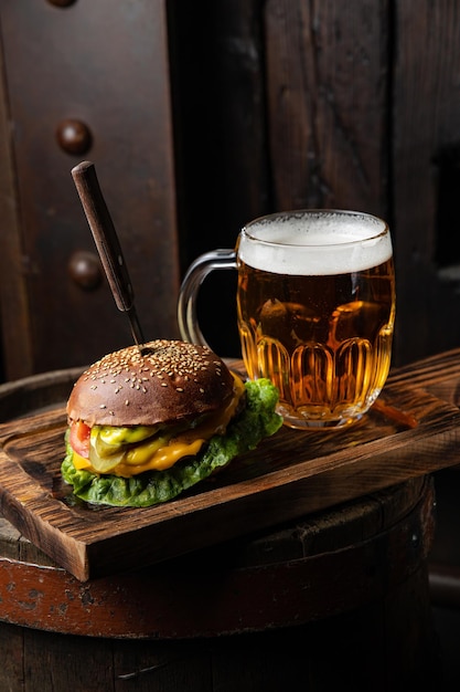 Um copo de cerveja e um hambúrguer em uma bandeja de madeira com uma caneca de cerveja.