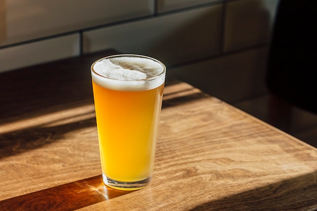 Um copo de cerveja em uma mesa de madeira.