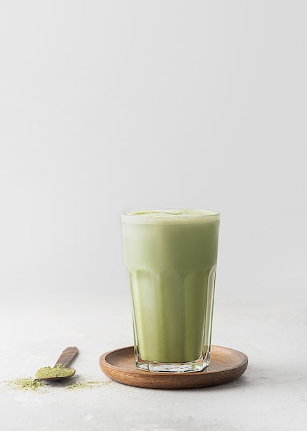 Um copo de chá matcha com leite em concreto cinza