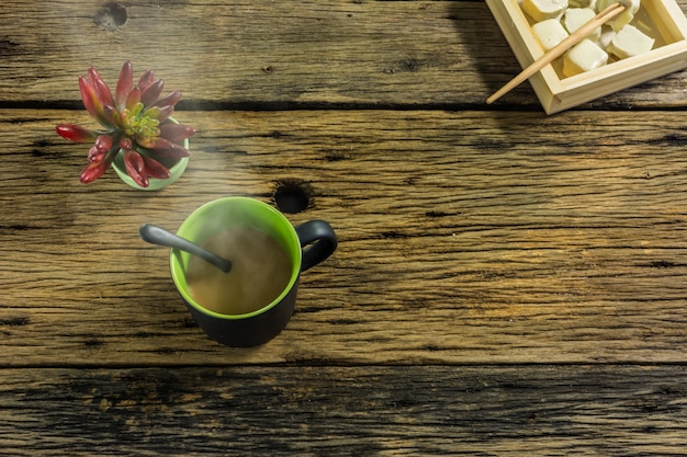 Um copo de chá quente na mesa de madeira velha.