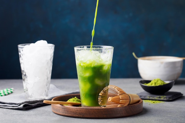 Um copo de chá verde com um líquido verde sendo derramado nele.