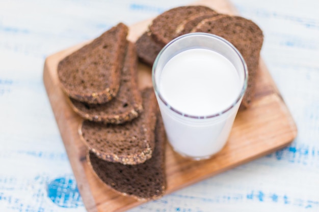 Um copo de kefir de leite e uma fatia de pão preto sobre fundo de madeira O conceito de dieta nutritiva saudável