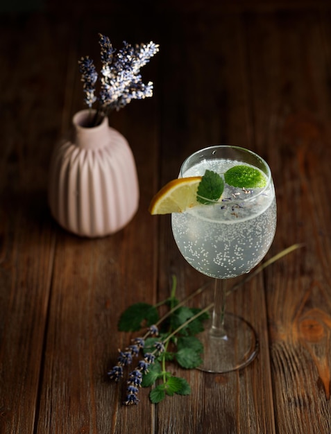 Um copo de limonada e um vaso de lavanda no fundo com textura de madeira