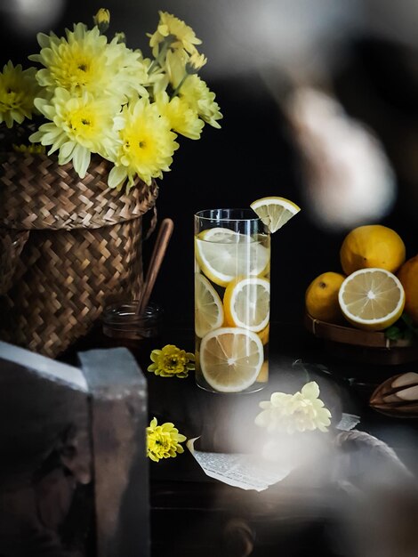 Um copo de limonada está sobre uma mesa com uma cesta cheia de flores.