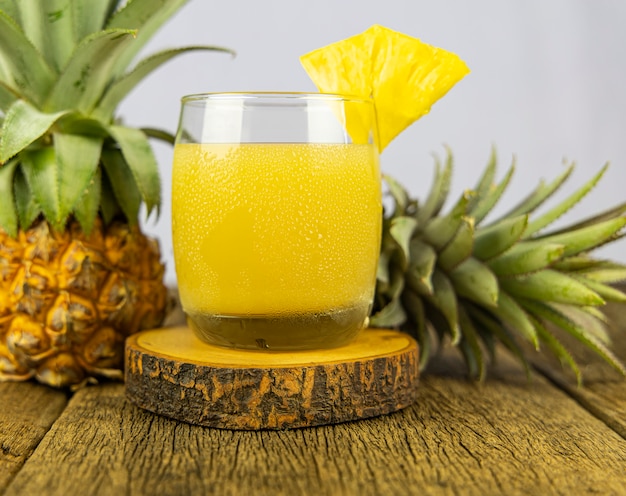 Um copo de suco de abacaxi no fundo da mesa de madeira.