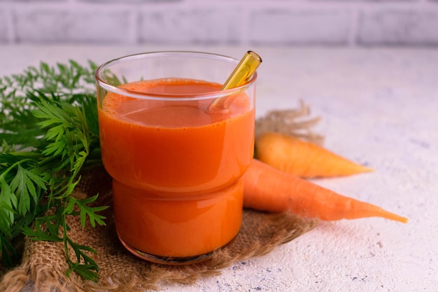 Um copo de suco de cenoura fresco em um fundo branco.