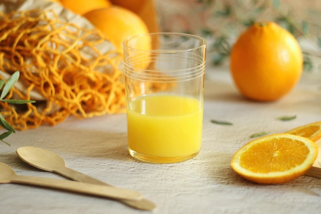 Um copo de suco de laranja caseiro ecologicamente correto natural em um copo e laranjas