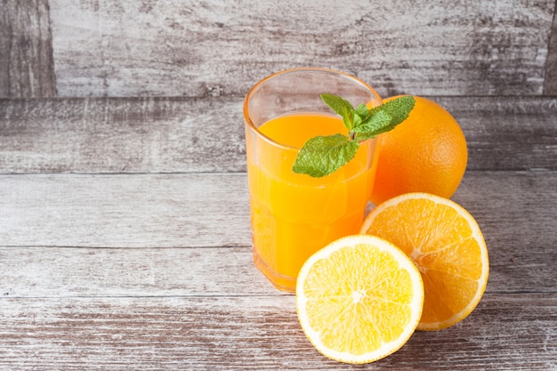 Um copo de suco de laranja com frutas laranjas