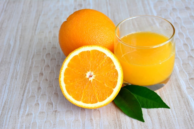 Um copo de suco de laranja com meia laranja em fundo pastel, close-up