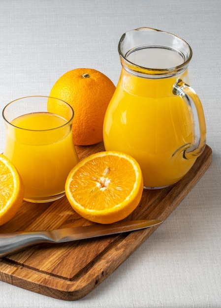 Um copo de suco de laranja fica em uma bandeja ao lado de uma jarra de suco de laranja.