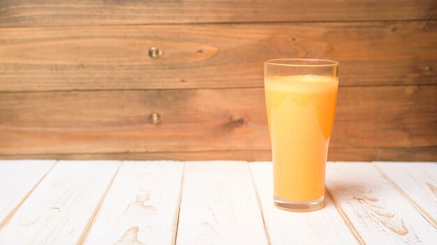 Um copo de suco de laranja na mesa de madeira