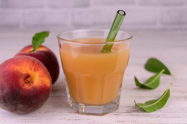 Um copo de suco de pêssego fresco em um fundo branco.