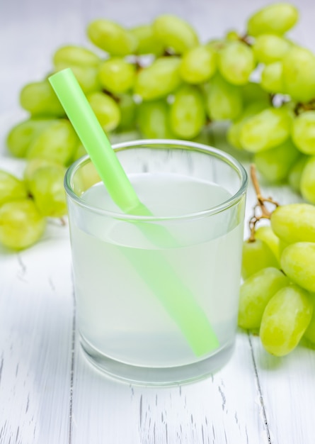 Um copo de suco de uva e uvas no fundo