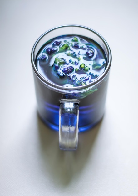Foto um copo de vidro transparente de chá de ervilha azul borboleta sobre fundo branco.