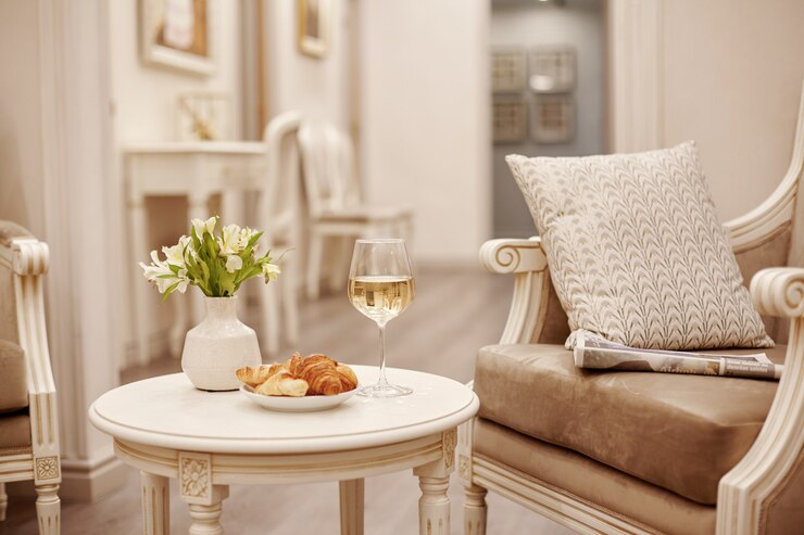 Um copo de vinho branco, croissants frescos e um vaso com flores brancas em uma mesa