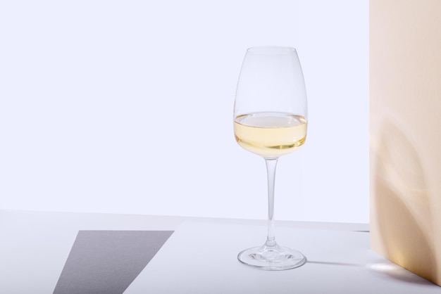 Um copo de vinho branco está sobre a mesa Fundo claro