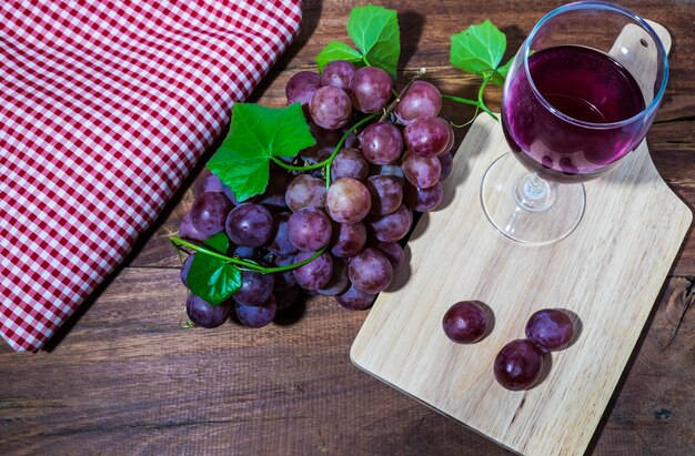 Foto um copo de vinho e uvas em uma mesa de madeira são lindamente definidos.