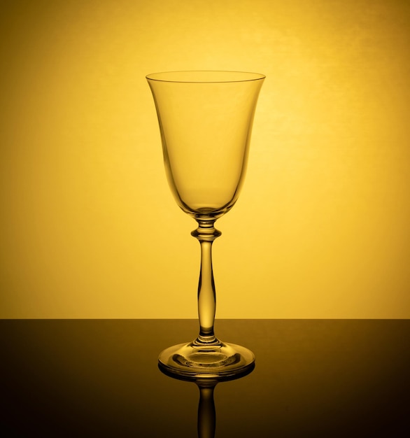 Um copo de vinho em um fundo laranja brilhante é refletido na superfície espelhada da mesa