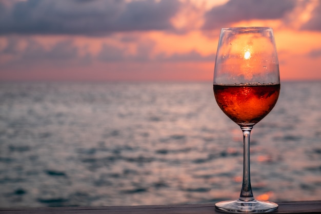 Um copo de vinho tinto no pôr do sol nas Maldivas