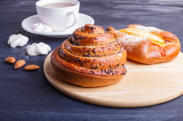 Um copo do chocolate quente e dos bolos na superfície de madeira preta.