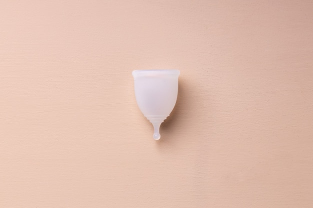 Um copo menstrual na vista superior do fundo bege
