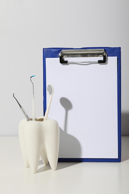 Um copo na forma de um dente com ferramentas dentárias