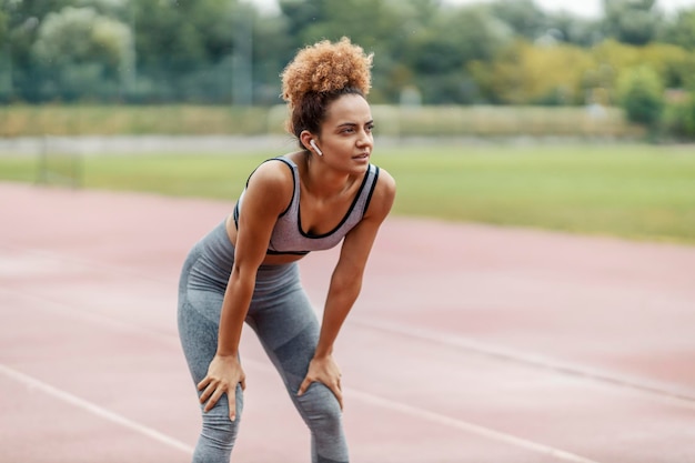 Um corredor cansado está parado no estádio e fazendo uma pausa depois de uma longa corrida