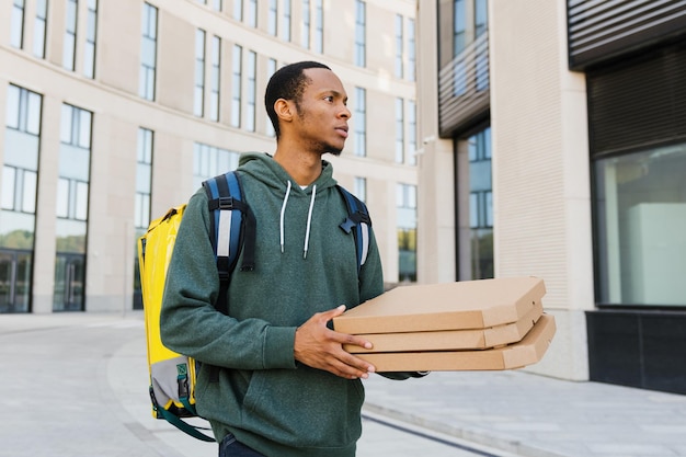 Um correio afro-americano com caixas de pizza fora da entrega profissional oportuna