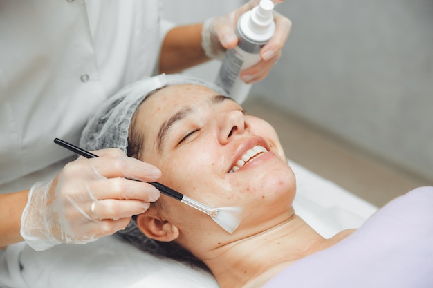 Um cosmetologista faz cuidados faciais e aplica uma máscara facial limpando um rosto muito sujo acne na pele erupções cutâneas pintura facial mecânica