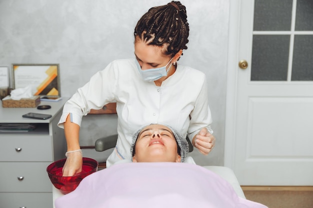 Foto um cosmetologista limpa a pele de um cliente de salão de beleza antes do procedimento e massagem facial o conceito de beleza e saúde cosmetologia pele coberta de espinhas