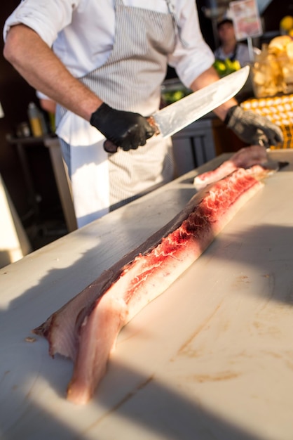 Um cozinheiro corta um peixe grande em pedaços no restaurante