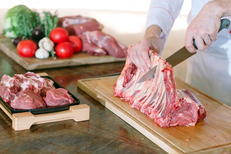 Foto um cozinheiro de homem corta carne com uma faca em um restaurante.